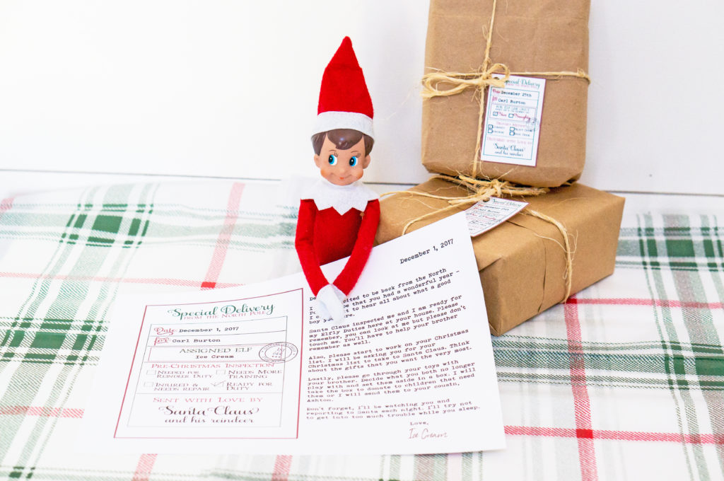 This image shows an example of the elf return letter free printable you can get at the end of this blog post. The elf on a shelf is sitting with two packages and an arrival letter from the North Pole. It shows an example of it with a filled out letter because it is an editable arrival letter.