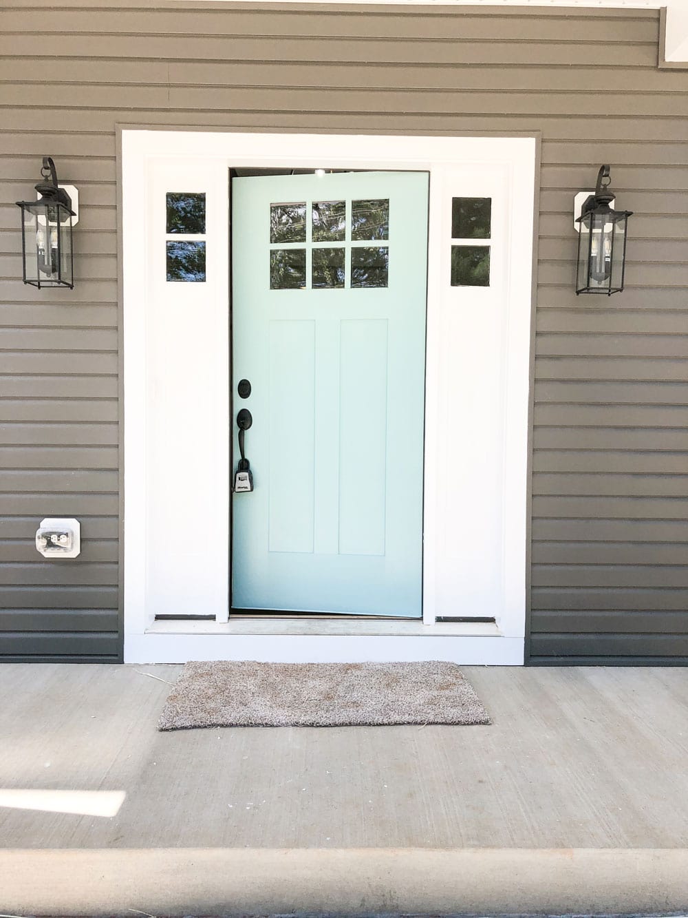 Custom home tour photos. This photo shows the blue door and porch. There are two black lights on either side of the door.