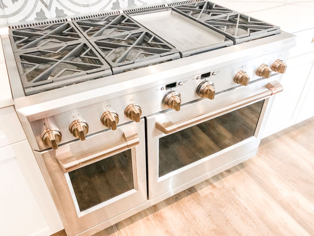 Custom home tour photos. This photo shows the 48 inch GE professional range. It has two ovens. It's stainless steel with gold knobs and handles. It has 6 large burners and a griddle.