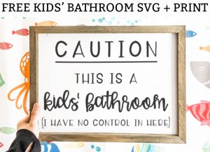 Funny Bathroom SVG and Print at the top in black text with a white background. Below it is a white sign with a wood frame. The sign in black text reads: Caution this is a kids' bathroom (I have no control in here). The background behind the sign is a white shower curtain with brightly colored fish and blue bubbles.