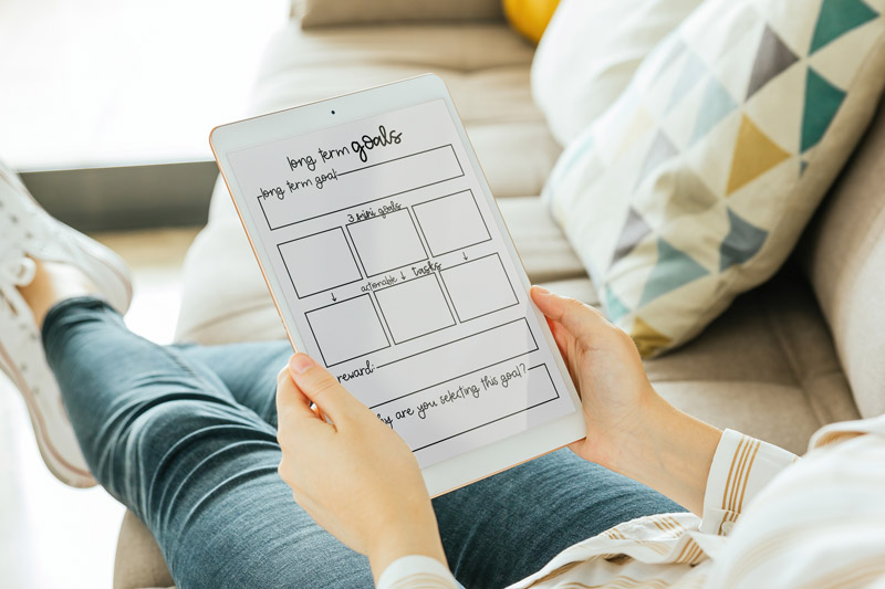 This image is of a girl looking at the free long term goal worksheet on an ipad. It's to show how the free files can be used digitally on tablets.