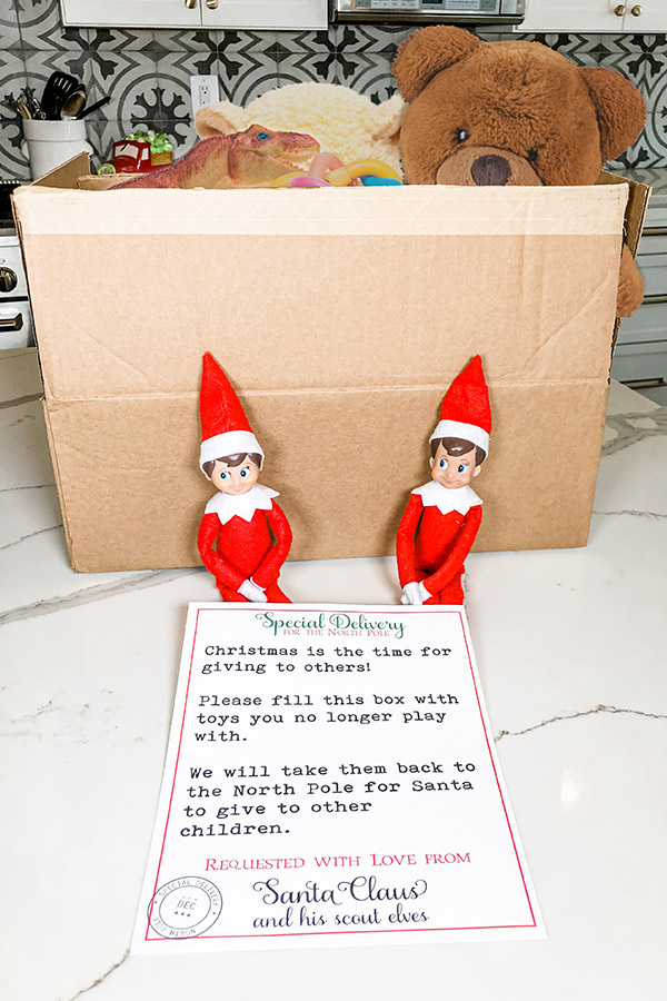 This image is for the post Elf on the Shelf Toy Donate Letter - it shows two elves on the shelf with a brown box and a copy of the free printable toy donation letter that is available to download in this blog post.