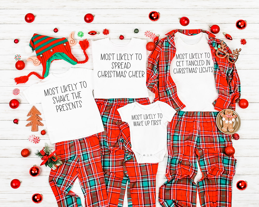 This image shows an example of the free SVG files in use. They're on white t-shirts paired with Christmas plaid pajamas. The shirts say: child's shirt - most likely to shake the presents, adult shirt #1 - most likely to spread Christmas cheer, adult shirt #2 - most likely to get tangled in Christmas lights, and a baby onesie says most likely to wake up first.