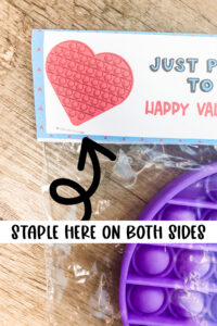 This image shows where you staple the free pop-it valentine that is available to download at the end of this psot.