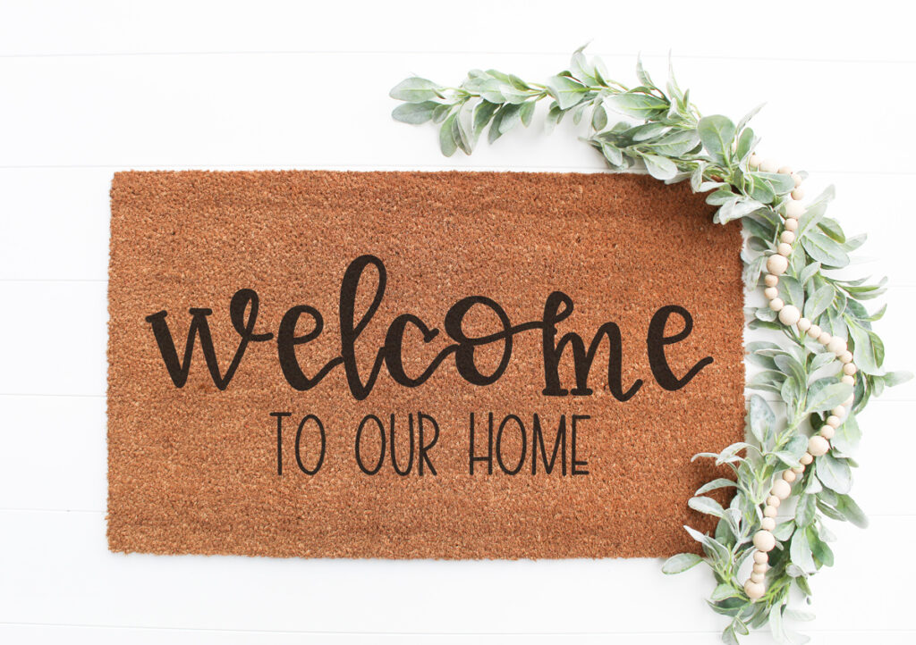 This image shows one of the two versions of the welcome to our home SVG files that are available to download for free at the end of this post. This image shows an example of the free welcome to our home SVG on a doormat.