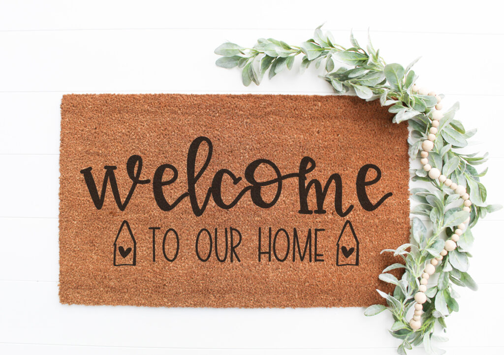 This image shows one of the two versions of the welcome to our home SVG files that are available to download for free at the end of this post. This image shows an example of the free welcome to our home SVG on a doormat.