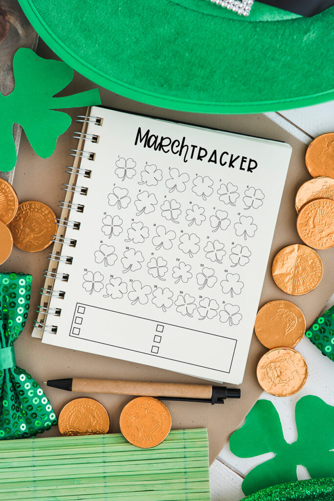 This image shows the March mood tracker available to download at the end of this post. It is is an image of the March mood and habit tracker on a notebook surrounded by St. Patrick’s day things like a paper green clover, a green St. Patrick’s day hat, gold coins, a green sequin bow tie, and a brown and black pen.