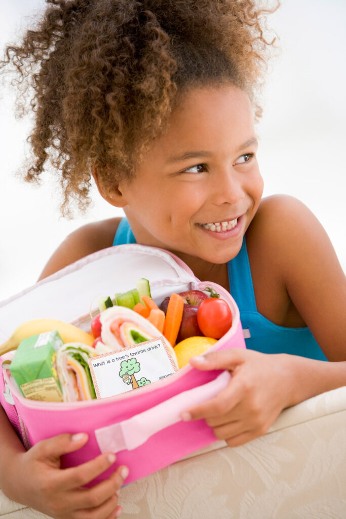 This image shows a little girl holding an open lunch box with one of the free spring lunch notes available to download at the end of this post.