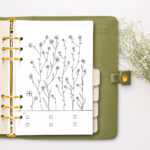 This image is of a green planner with gold rings opened up to the free May Mood tracker you can download at the end of this blog post.