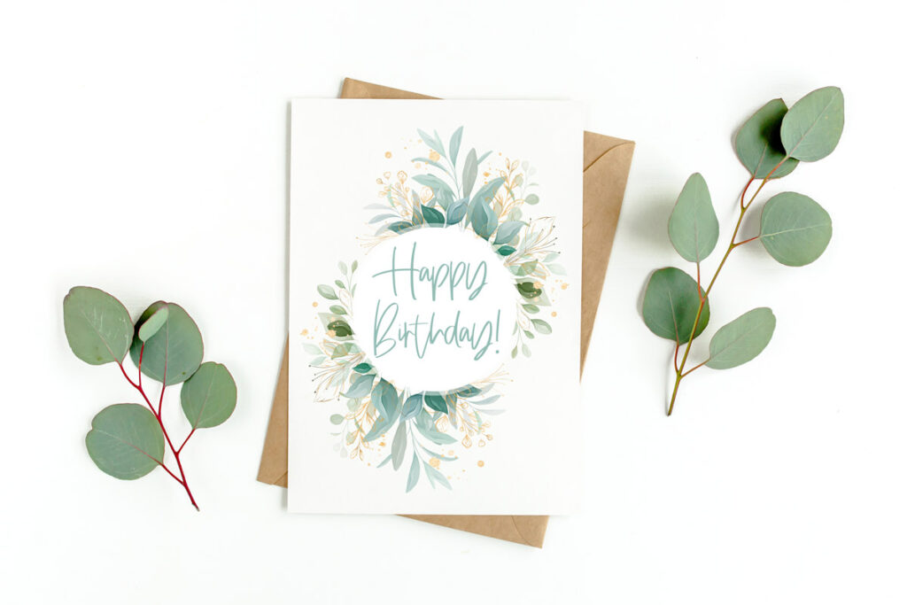 This image shows an example of a flower birthday card you can download for free in this set of 8 free printable birthday cards. This image shows a card with a circle of green foliage with a gold happy birthday in the middle. At the left and right are a sprig of green leaves.