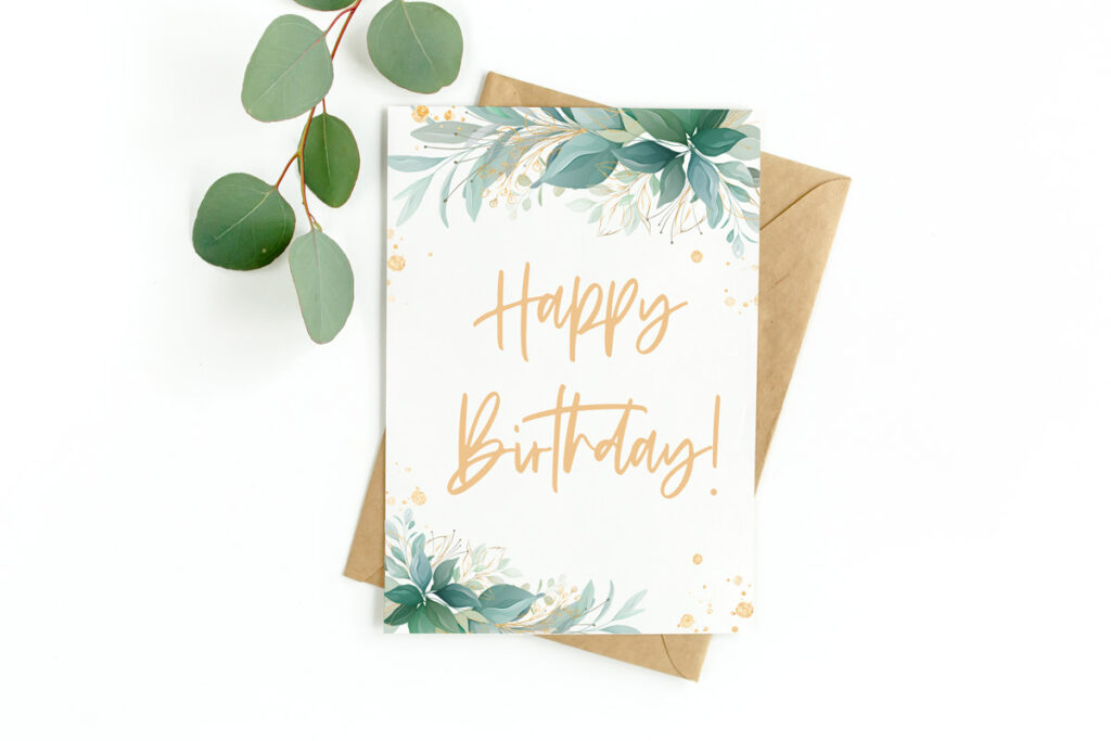 This image shows an example of a flower birthday card you can download for free in this set of 8 free printable birthday cards. This image shows a card with green foliage at the top right and bottom left corners of the card with a gold happy birthday in the middle. At the left and right are a sprig of green leaves.