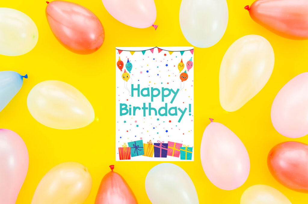 Get this free printable birthday card at the end of this blog post. This image shows a yellow background and a bunch of balloons. In the center is the free birthday card printed out.