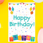 Get this free printable birthday card at the end of this blog post. This image shows a yellow background and a bunch of balloons. In the center is the free birthday card printed out.