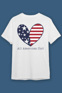 This image shows one of the free 4th of July SVG designs on a white t-shirt. It is a drawing of a heart with a blue half with white stars and a red and white striped half. Under the heart is says all American girl in print.