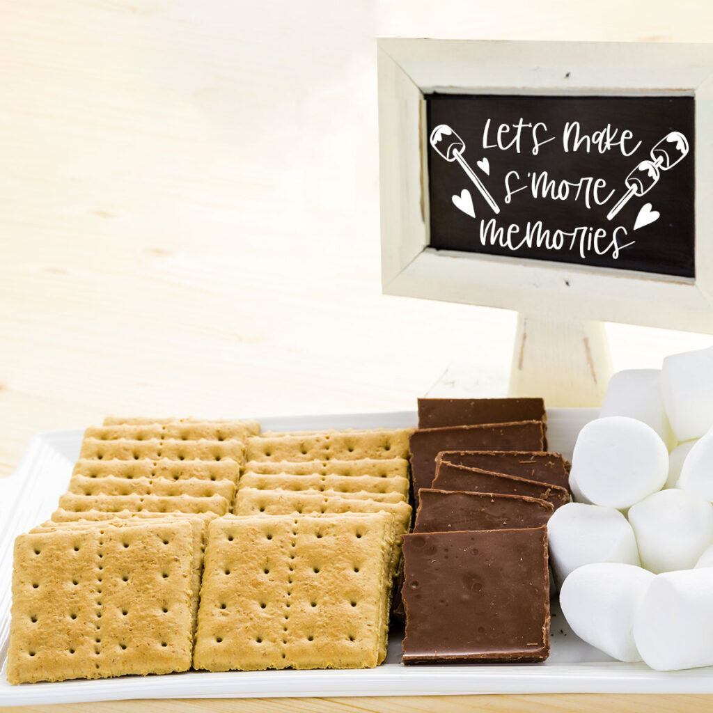 This shows some s'mores making supplies set up in a s'mores station with a copy of the making smore memories SVG in a little stand above the s'mores ingredients.