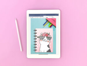 This image shows an example of what the cover looks like for the free digital cat planner. The image is of a white iPad open to a Goodnotes Digital file. The cover has a gray and white cat on it with a pink floral headband.