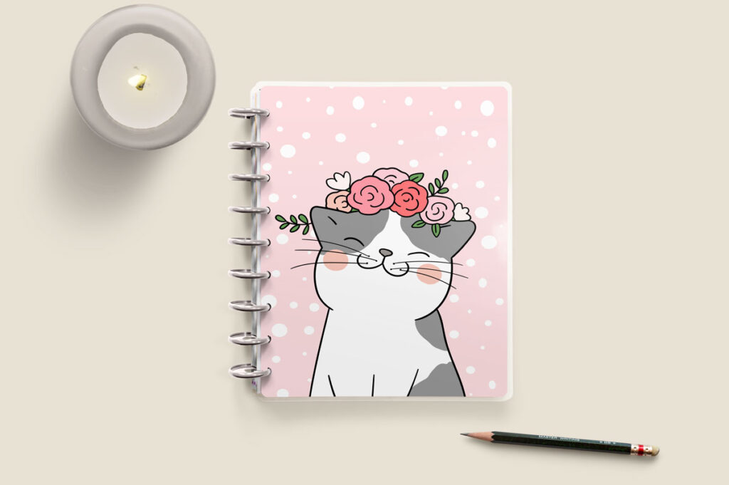 This is an image of the front cover from the Free Cat Planner Cover Printables available to download at the end of this blog post. The cover is light pink with white polka dots. There is a gray and white cat in the bottom middle of the cover with a pink floral crown. There is a candle burning in the top left corner and a pencil in the bottom right corner.