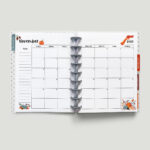 This image is of a planner open to a 2023 calendar with holidays. This is one of the options you can download at the end of this blog post. This image shows a 2023 November calendar with a Sunday start. It has a pumpkin and floral design.