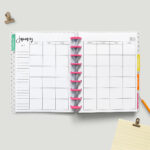 This image shows the free printable 2023 calendar you can get for free at the end of this blog post. This image shows a simple Classic Happy planner with pink discs opened up to a January 2023 monthly calendar spread.