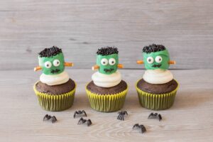 This image shows one of the kids Halloween party foods that is rounded up in this post. This is showing a frankenstein's monster cupcake.