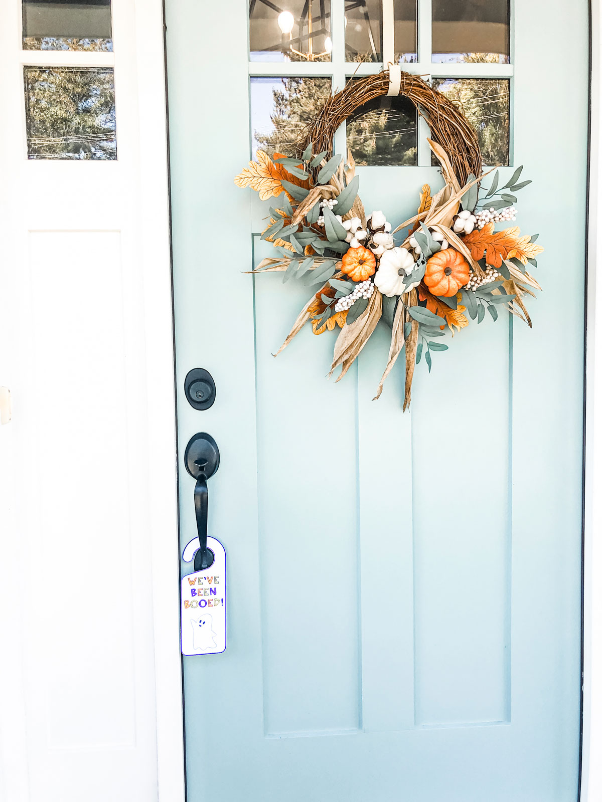 This image shows the you’ve been booed door hanger you can get for free in the You’ve been Booed printable set at the end of this blog post. It’s a white door hanger with a purple outline. It has a little ghost and says, “You’ve been booed!” It is hanging on a front door.