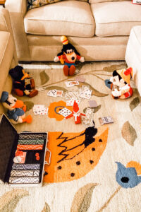 This image shows an elf on the shelf playing a game of poker with four stuffed animals. This is one of the many elf on the shelf ideas for home included in this post.