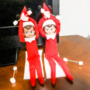 This image shows elf on the shelf dolls pretending to work out with dumbells made out of toothpicks and mini marshmallows, This is one of the many elf on the shelf ideas for home included in this post. Use a unicorn, horse, elephant, etc. toy to create this magical elf on the shelf scene. This is one of the 50+ elf on the shelf ideas for home included in this round up. Plus, you’ll get a set of free Elf on the Shelf planning printables. This includes a blank elf on the shelf calendar, list of elf on the shelf ideas, printable elf on the shelf notes, a fillable elf on the shelf note set, and more.