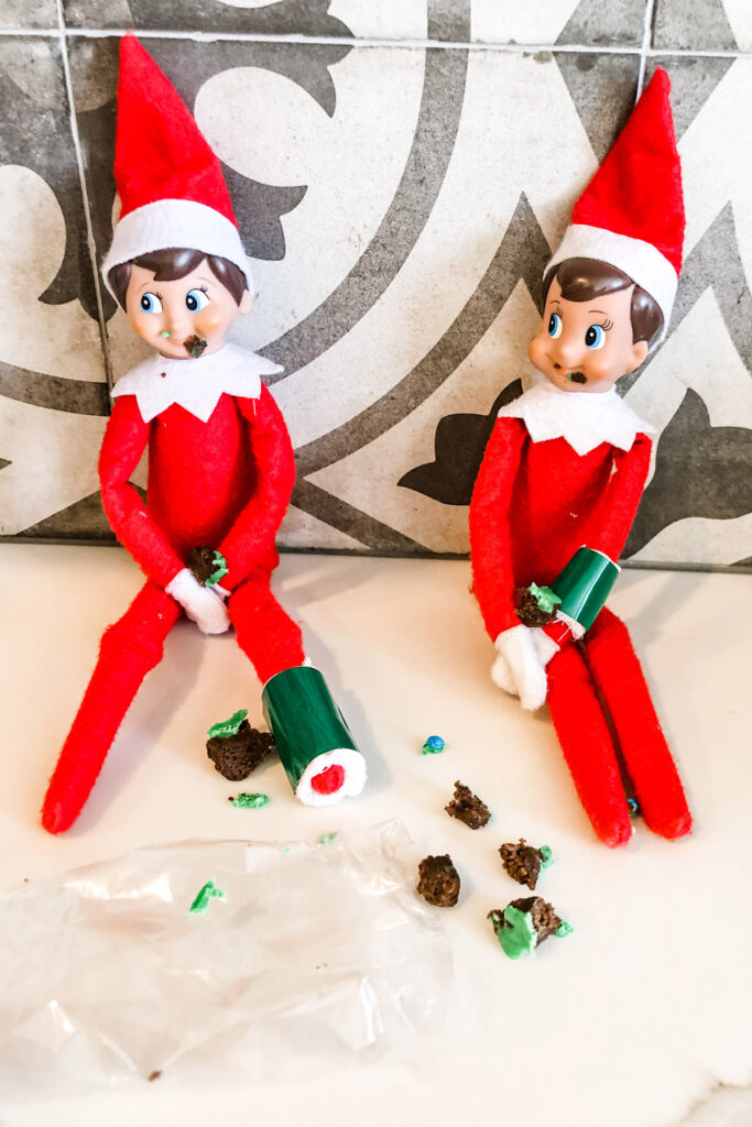 This image shows elf on a shelf dolls eating a brownie. This is one of the many elf on the shelf ideas for home included in this post.