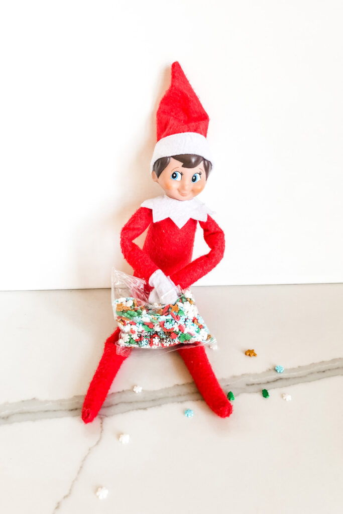 This image shows an elf eating some holiday themed sprinkles. This is one of the many elf on the shelf ideas for home included in this post.