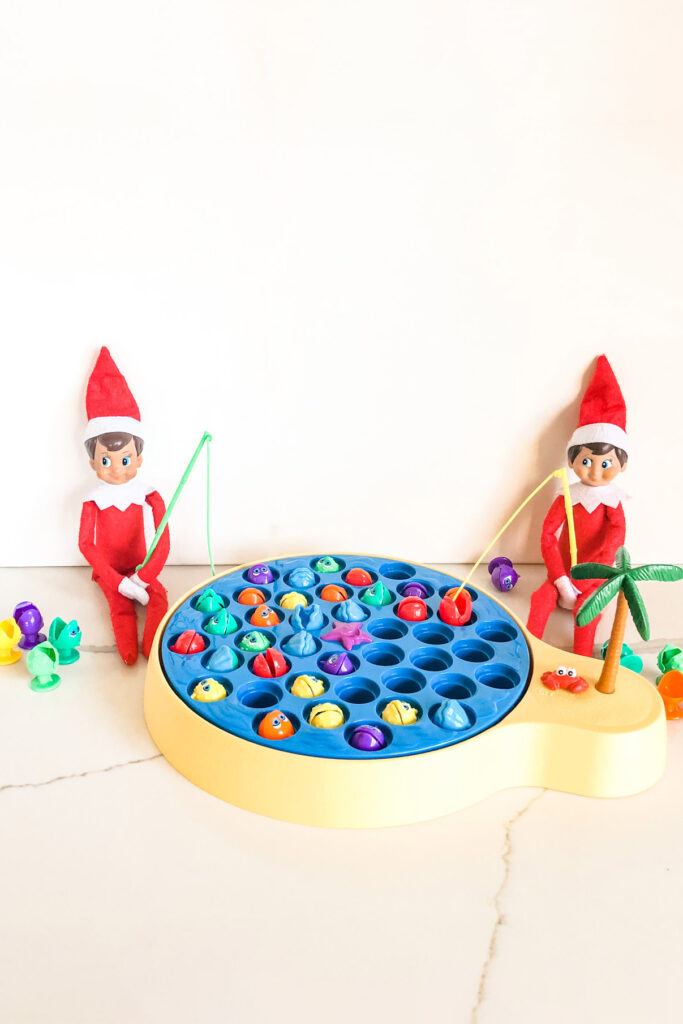 This image shows two elves playing a game a game of Let’s Go Fishing. This is one of the many elf on the shelf ideas for home included in this post.