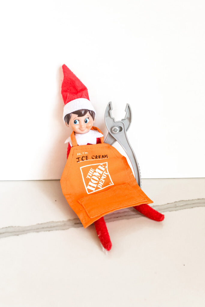 This image shows an elf on the shelf with a little Home Depot apron and toy wrench. This is one of the many elf on the shelf ideas for home included in this post.