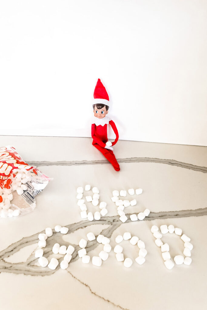 There is an elf with the words be good spelled out with mini marshmallows. This is one of the many elf on the shelf ideas for home included in this post. Use mini marshmallows or small candy to write out special messages from the elves. Learn more tips and tricks with over 50 Elf on the Shelf ideas for home. There are tons of easy ideas, funny ideas, last minute ideas, and more. Plus, you’ll get a set of free Elf on the Shelf planning printables. This includes a blank elf on the shelf calendar, list of elf on the shelf ideas, printable elf on the shelf notes, a fillable elf on the shelf note set, and more.