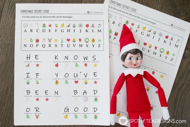 In this image, there is an elf on the shelf shown with a Christmas secret code printable. This is one of the many elf on the shelf ideas for home included in this post.