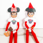 This image shows two Elf on the Shelf dolls wearing their free Elf on the Shelf Mouse Ears and Snacks printable items that you can get for free at the end of this blog post.