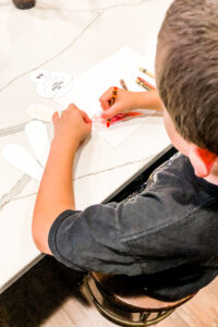 This is an image of a boy coloring the free Thanksgiving thankful turkey printable you can get for free at the end of this blog post.