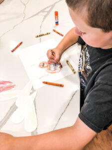 This is an image of a boy coloring the free Thanksgiving thankful turkey printable you can get for free at the end of this blog post.