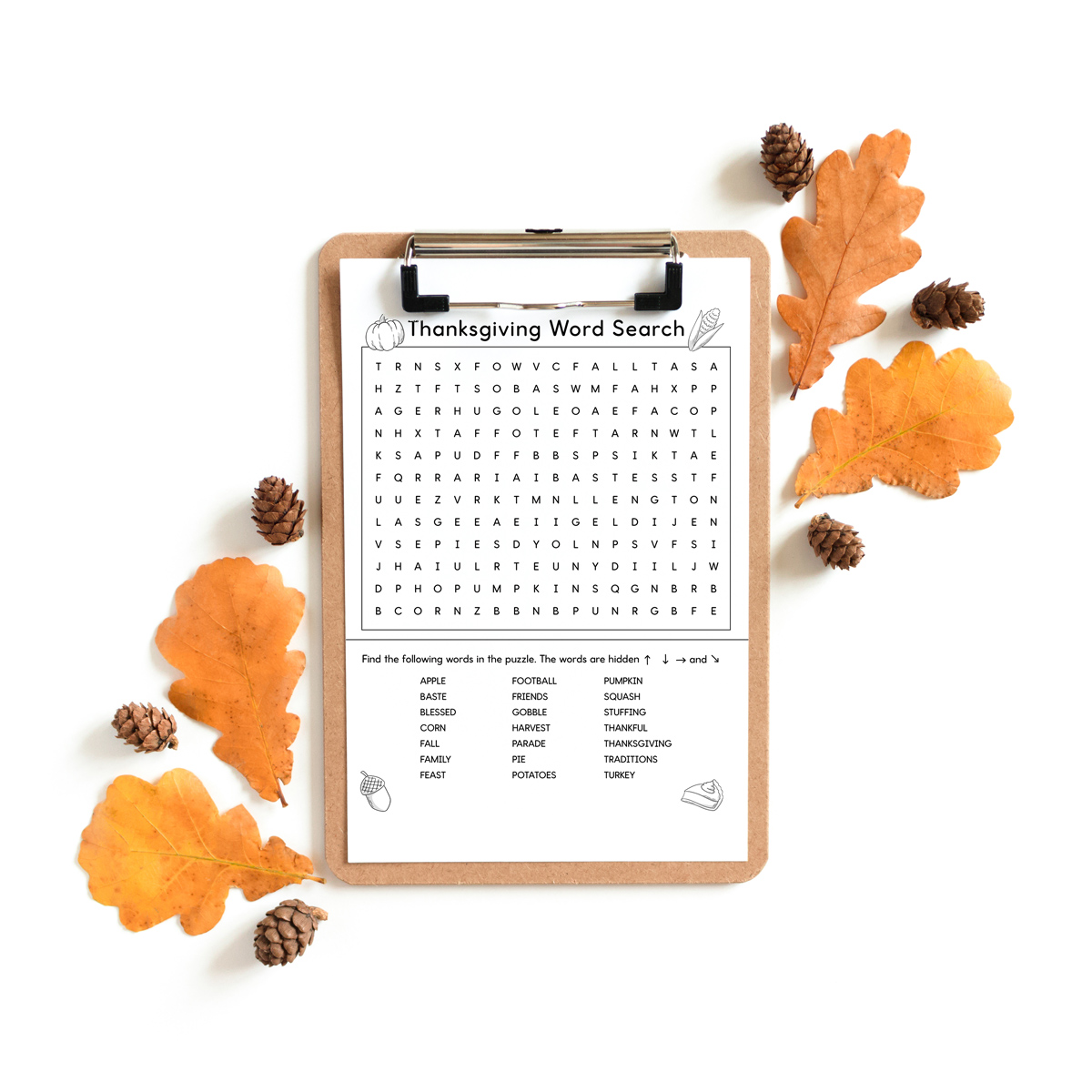 This image shows a Thanksgiving Word search printable which you can get at the end of the blog post. This example is showing the medium version. The word search is on a wooden clipboard and is surrounded by a few leaves and small pine cones. At the top of the word search, it says Thanksgiving word search. Below that is a grid of letters. Underneath that is a list of Thanksgiving themed words to search for (such as turkey, fall, football, and more). This example also has black and white Thanksgiving clip art including a pumpkin, ear of corn, acorn, and slice of pumpkin pie. 
