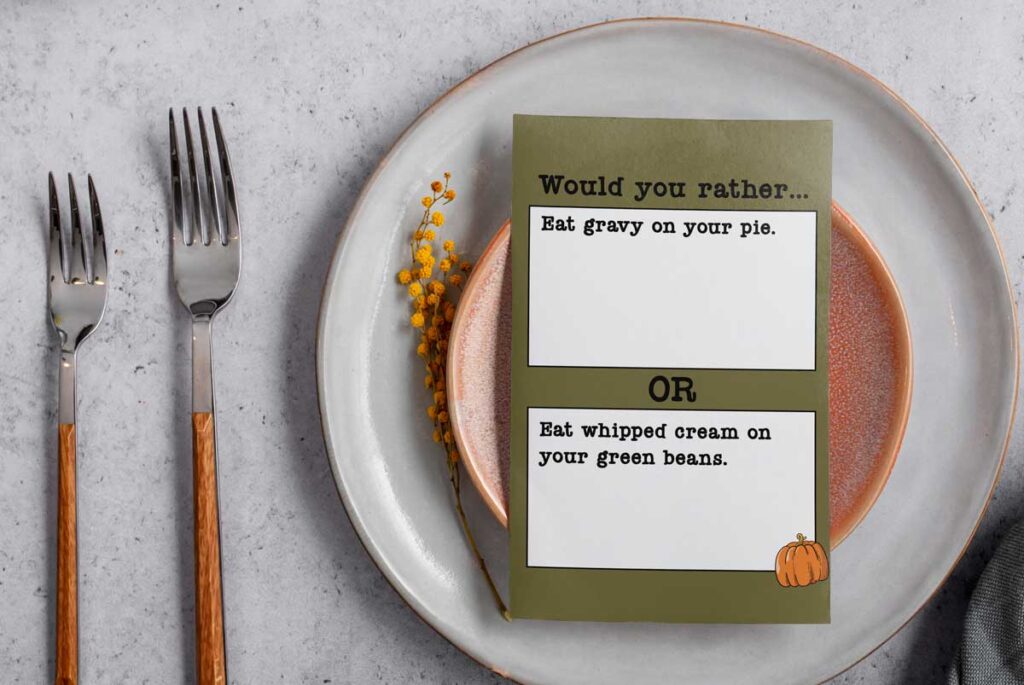 This image shows one of the question cards from the Would you Rather Thanksgiving games printable. There are twenty Thanksgiving would you rather question cards included in this free set you can get in this blog post. This question says, would you rather eat gravy on your pie or eat whipped cream on your green beans. The card is sitting on a plate and has silverware next to it.