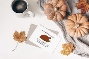 This image shows one of the printable thanksgiving cards you can get for free at the end of this post. This card says Happy Thanksgiving! May your turkey be moist (and may no one use that word to describe it). It has the picture of a cooked turkey on a platter. The card is surround by a mug of coffee, pumpkins, and leaves.