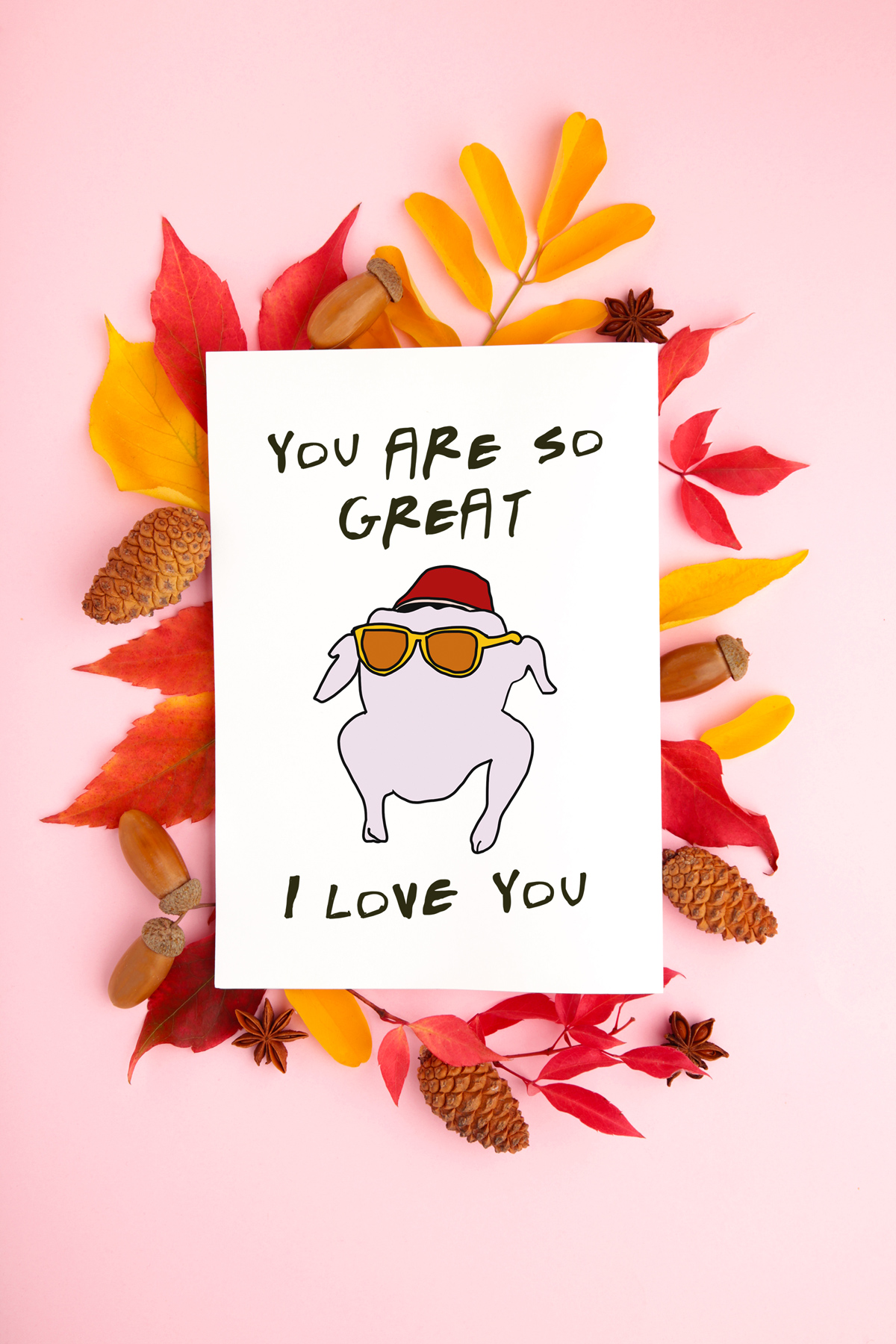 This image shows one of the printable thanksgiving cards you can get for free at the end of this post. This card says you are so great I love you with a raw turkey with yellow sunglasses and a hat (to look like the one from the Thanksgiving episode of Friends). The card is surrounded by leaves, across, and pine cones.