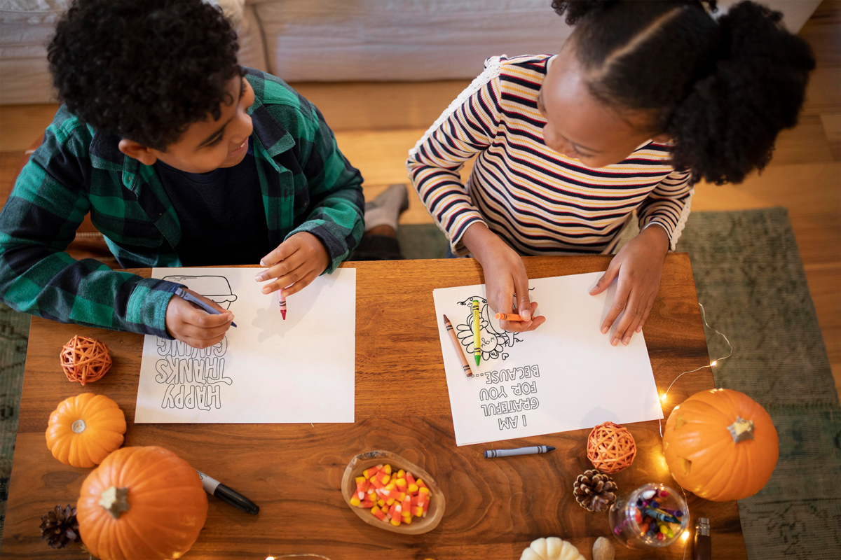 The image shows two children coloring two of the cards from the Thanksgiving cards coloring pages set.