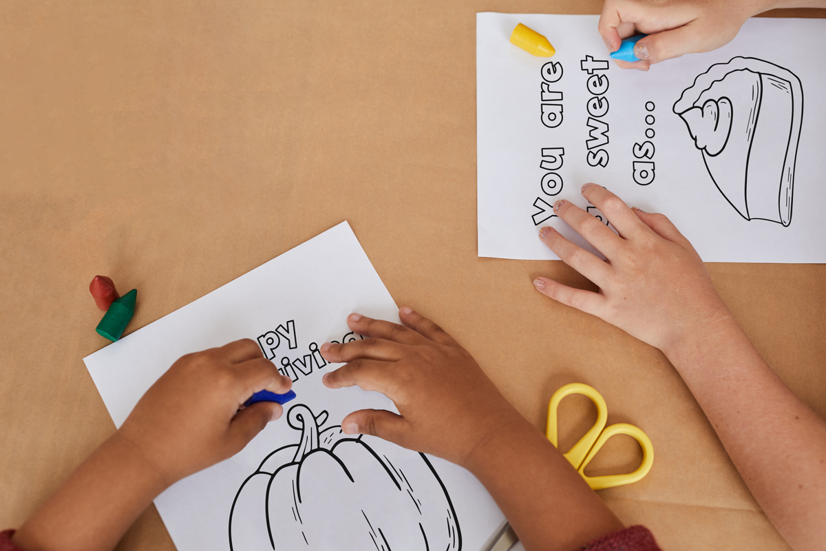 The image shows two children coloring two of the cards from the Thanksgiving cards coloring pages set.