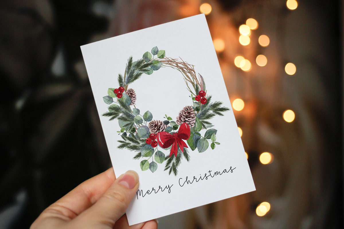 This image shows one of the designs you can get in this free Merry Christmas printable set of cards and prints. It says Merry Christmas on it and has a picture of a Christmas wreath.