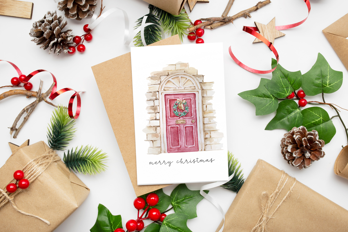 This image shows one of the designs you can get in this free Merry Christmas printable set of cards and prints. It says Merry Christmas on it and has a picture of a front door with a Christmas wreath on it.