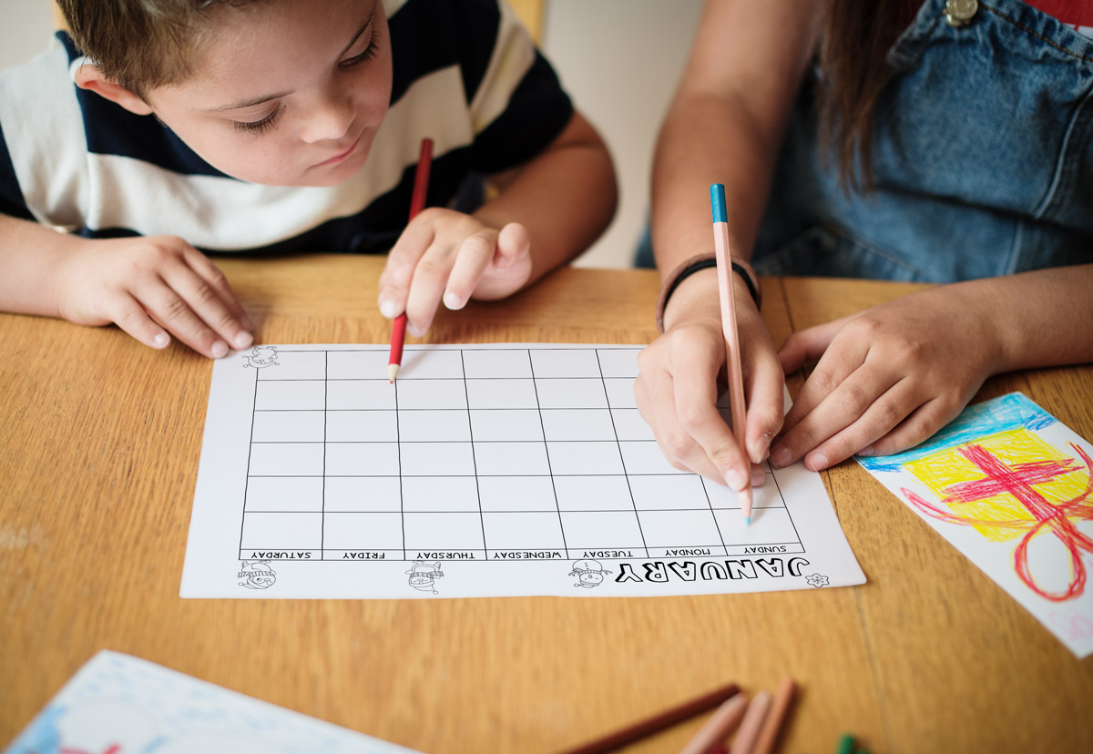 This image shows a pair of children looking at one of the months from the printable calendar for kids. This one is the month of January without clip art.