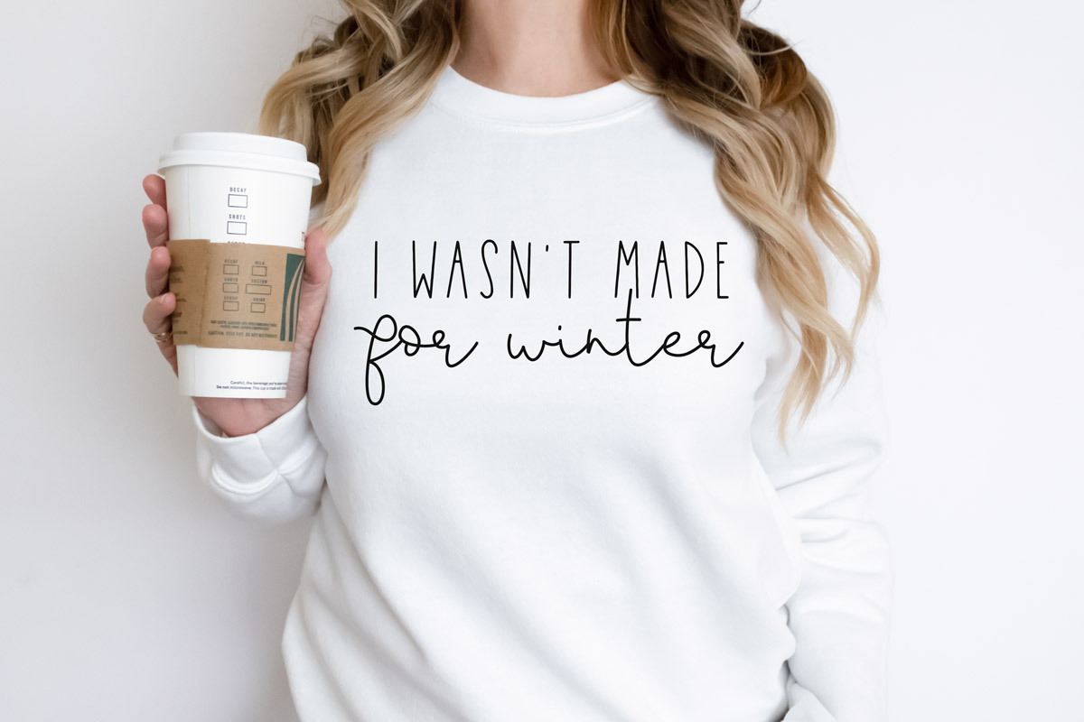 This image shows one of the free winter SVGs you can get at the end of this blog post. The SVG showing is on a sweatshirt and says, “I wasn’t Made for Winter.”