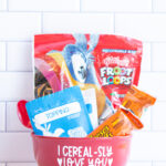 This image shows the I cerealsly love you SVG applied to a red cereal bowl. The bowl has a bag of cereal, two cereal bars, a bag of oatmeal, and a red spoon sitting inside of it.