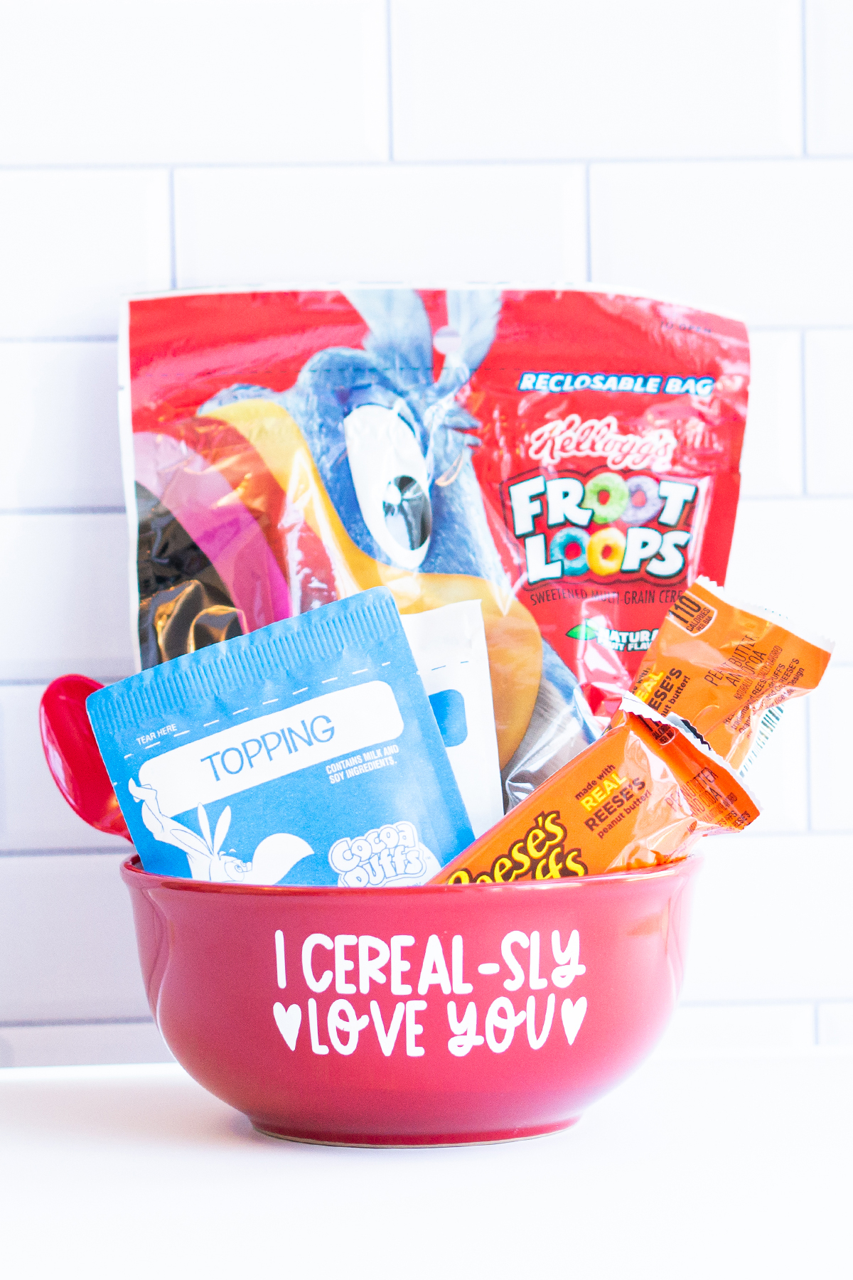 This image shows the I cerealsly love you SVG applied to a red cereal bowl. The bowl has a bag of cereal, two cereal bars, a bag of oatmeal, and a red spoon sitting inside of it.