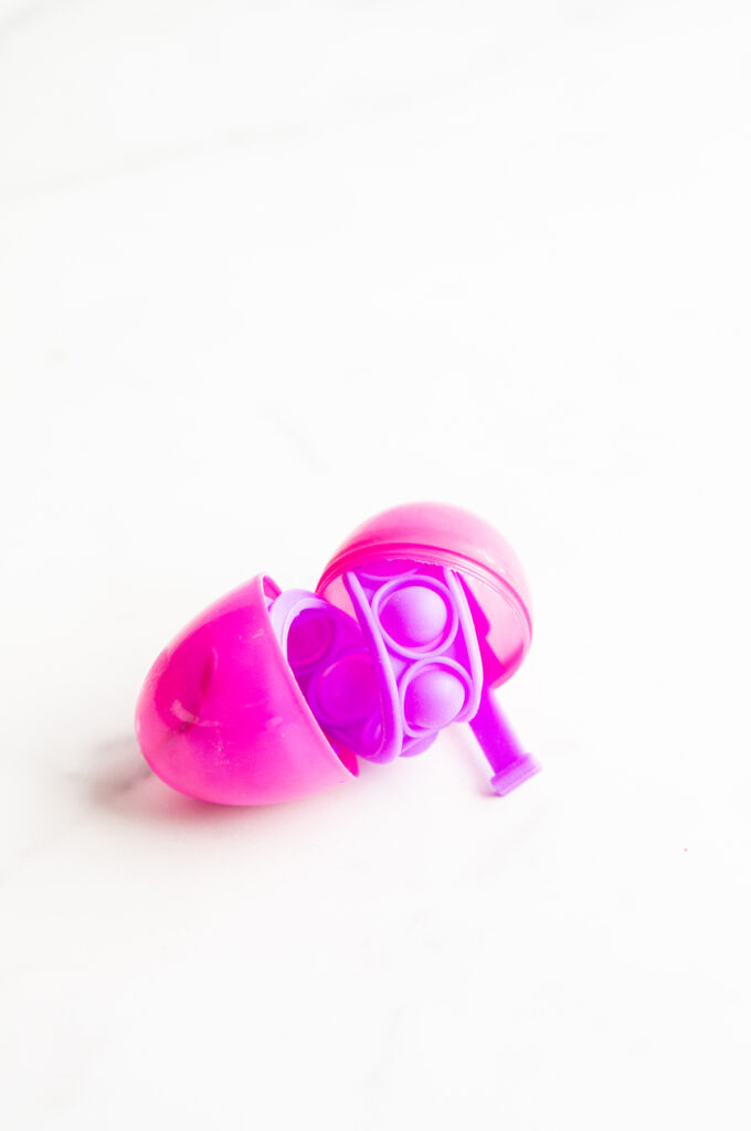 This image shows a plastic easter egg filled with non candy item of pop it bracelet.