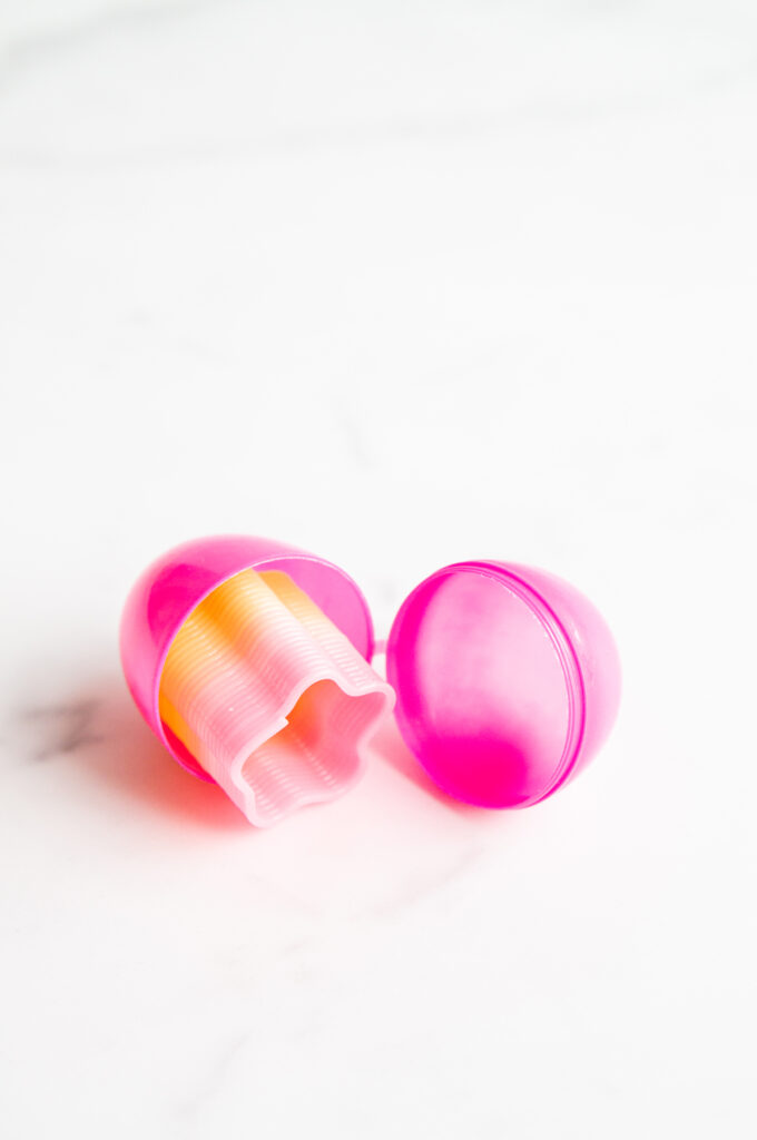 This image shows a plastic easter egg filled with non candy item of a mini slinky.